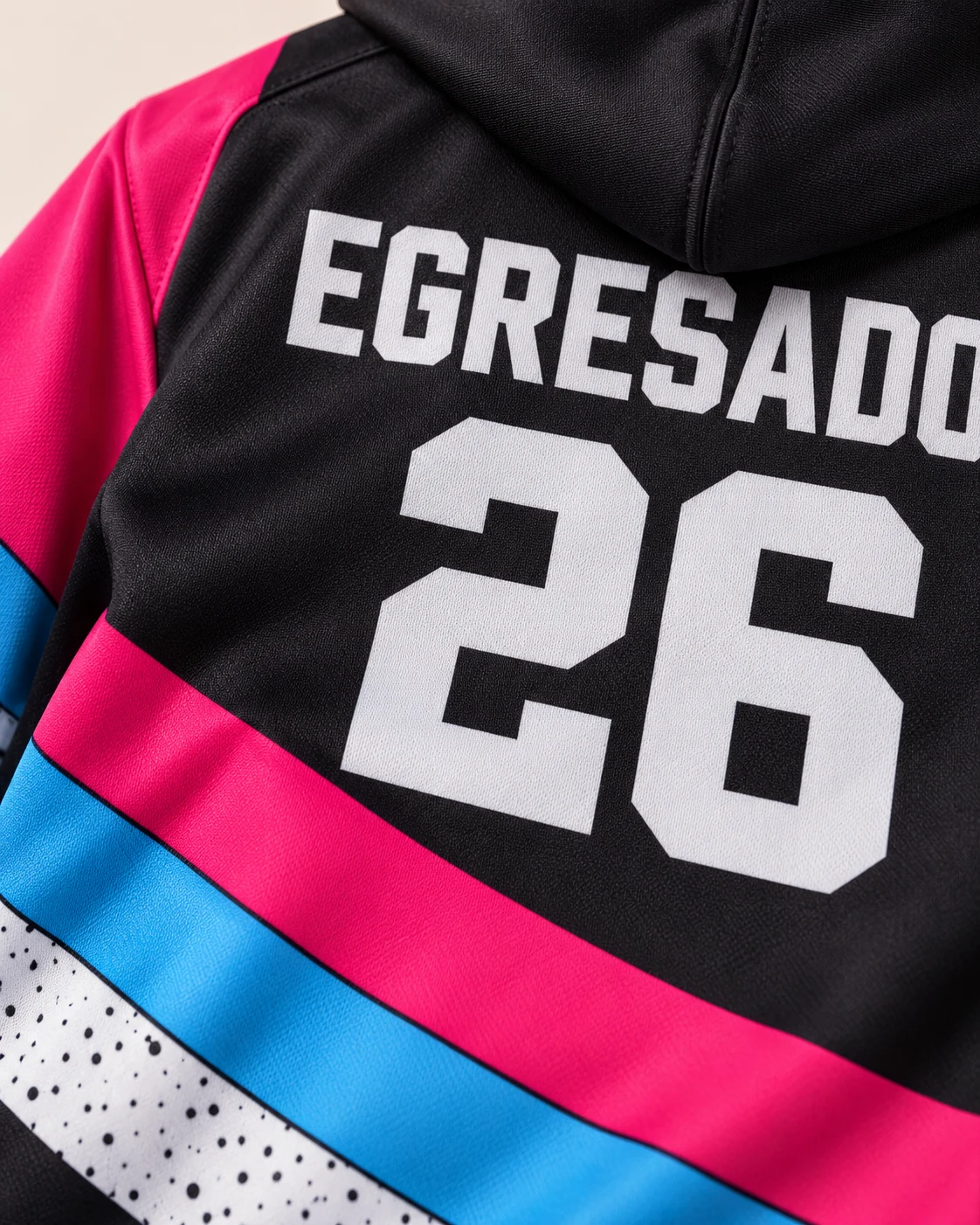 Campera negra con franjas fucsia, celeste y blanca y diseño Egresados 26 sublimado sobre tela deportiva. Vista de detalle.
