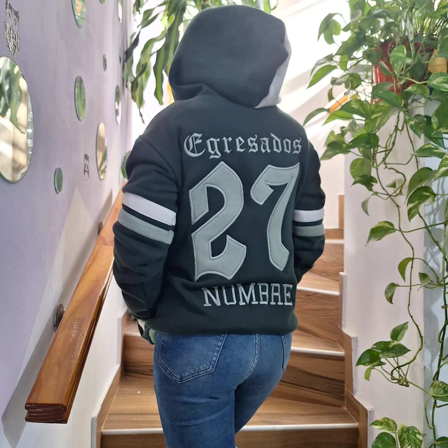 Espalda de un buzo oscuro con Egresados y el número 27 bordados.
