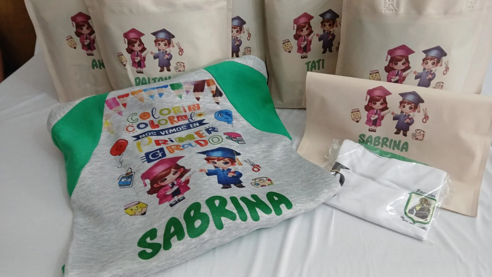 Prenda gris con mangas verdes y bolsas personalizadas para primer grado.